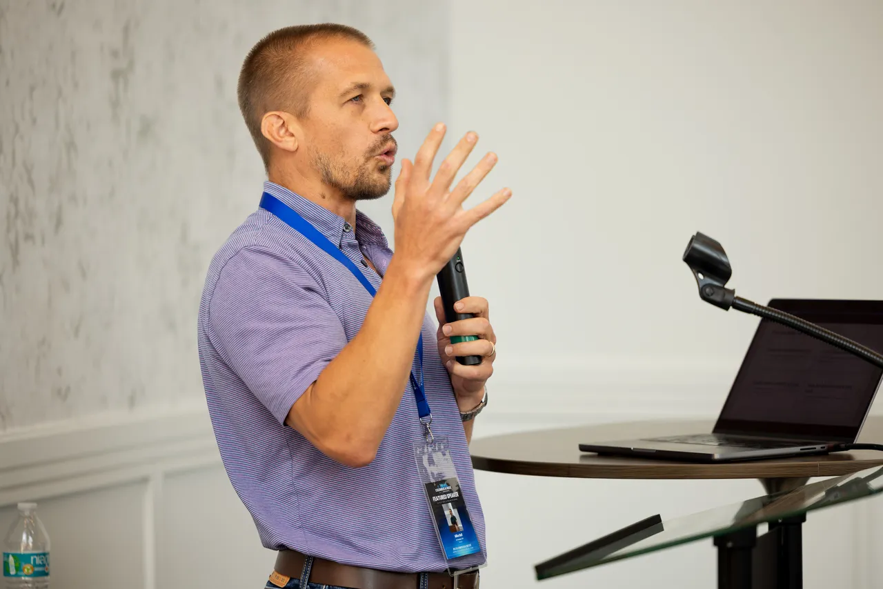 Mike Bell speaking into a microphone during a presentation